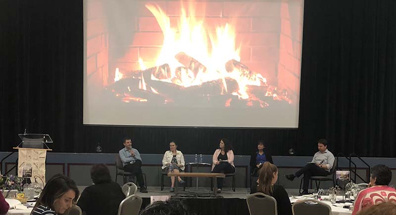 four NH employees sitting in front of a large screen displaying a fireplace 