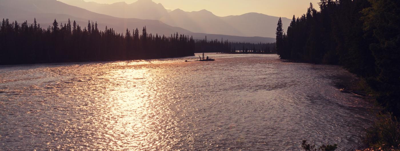 Setting sun over rippled lake and mountains behind