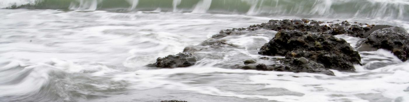 Wave breaking on rocks and pebble beach