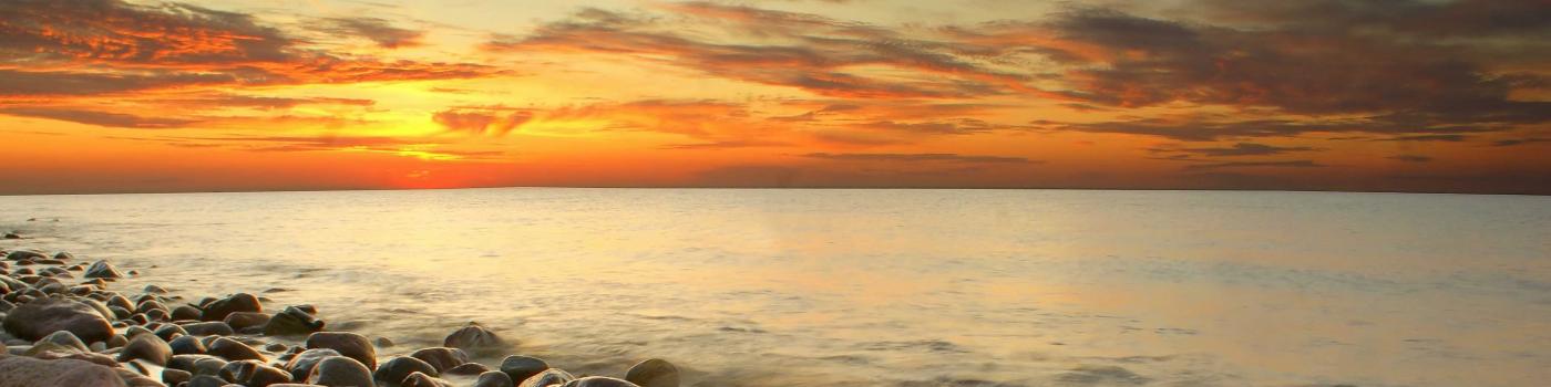 Orange sunset over the ocean and a rocky beach