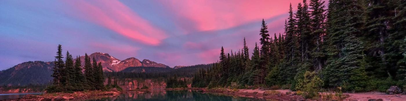 Pink sunset reflected over lake and mountains