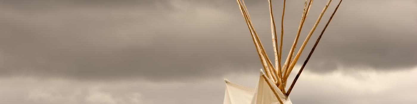 Top of a teepee against a dark grey sky