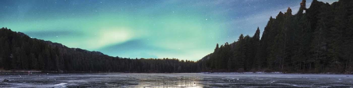 Northern lights over a lake with trees on the horizon