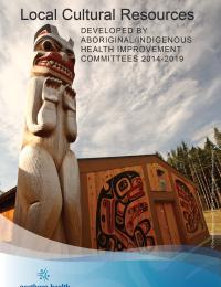 Totem pole beside a wood building with Indigenous art on the front